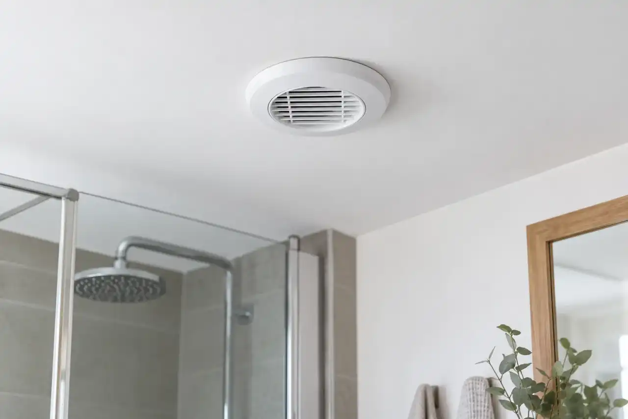 Bouche de VMC blanche au plafond d'une salle de bain